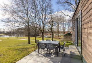 View from Chalet Comfort 6 terrace at Hunzepark in the Netherlands, with outdoor dining set and lake.