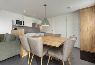 Comedor moderno y cocina en Chalet Comfort 6 en Hunzepark, Países Bajos, con seis sillas y mesa de madera.