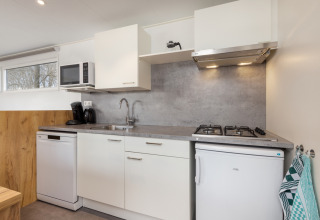 Cocina moderna en Chalet Comfort 6 en Hunzepark, Países Bajos, equipada con nevera, fregadero y microondas.