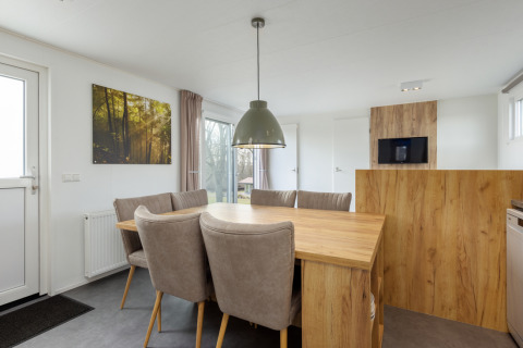 Zona pranzo nel Chalet Comfort 6 di Hunzepark, Paesi Bassi, con tavolo in legno e sedie comode.