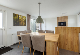 Dining area in Chalet Comfort 6 at Hunzepark, Netherlands, featuring a wooden table and cozy chairs.