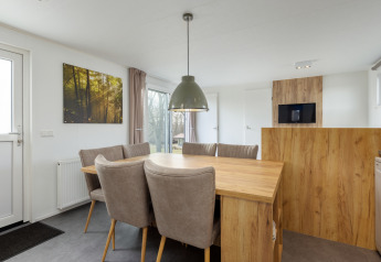 Spiseområde i Chalet Comfort 6 ved Hunzepark, Nederlandene, med træbord og blødestole.
