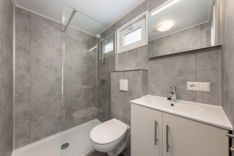 Baño moderno con ducha de cristal, inodoro y lavabo en el Chalet Comfort 6 de Hunzepark, Países Bajos.