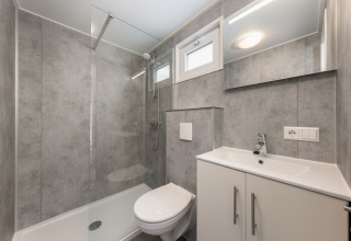 Baño moderno con ducha de cristal, inodoro y lavabo en el Chalet Comfort 6 de Hunzepark, Países Bajos.