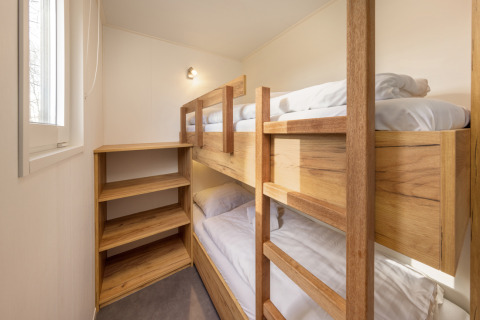 Habitación luminosa con literas de madera y estantería en Chalet Comfort 6 en Hunzepark, Países Bajos.