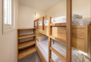 Stanza luminosa con letti a castello in legno e scaffalature presso Chalet Comfort 6 a Hunzepark, Paesi Bassi.