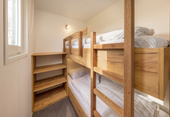 Lyst værelse med robuste køjesenge i træ og indbygget reol på Chalet Comfort 6 i Hunzepark, Nederlandene.