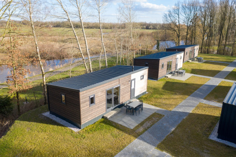 Vista aérea de los chalets Comfort 6 en Hunzepark, Países Bajos, rodeados de vegetación y árboles.
