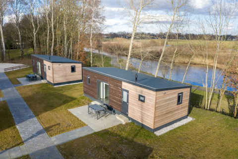 Dos cabañas Chalet Comfort 6 en Hunzepark, Países Bajos, junto a un lago y rodeadas de naturaleza.