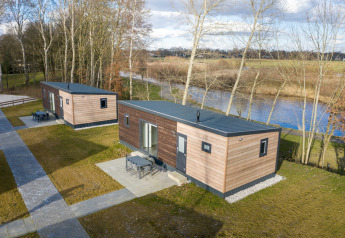 To Chalet Comfort 6-hytter ved Hunzepark i Nederlandene med udsigt over en sø og omgivet af natur.