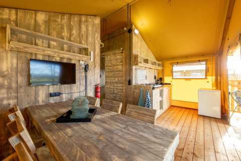 Interior de una tienda safari en Hunzepark, Países Bajos, con muebles de madera y cocina pequeña.