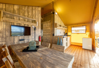 Interior of Safari Tent 6 at Hunzepark in the Netherlands, featuring wood furniture and kitchenette.