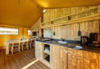 Indvendig udsigt af Safari telt 6 på Hunzepark i Holland med træmøbler og køkkenudstyr.