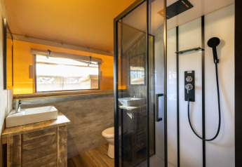 Badeværelse i Safari telt 6 på Hunzepark i Holland med brusekabine, håndvask og toilet i naturlige toner.