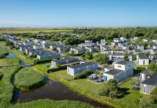 Luftfoto af feriehytter i Callassande feriepark, omgivet af grønt område og kanaler i Nordholland.