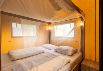Interieur van safaritent 'Safaritent 4' op Callassande in Nederland met bed en klamboe.