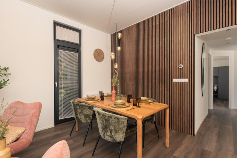Elegantes Esszimmer im Cannenburch Deluxe Lodge, Holzlattenwand, grüne Stühle und Holztisch.
