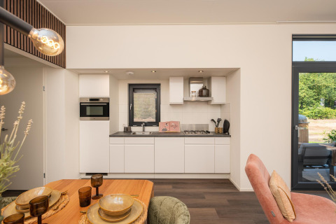 Moderne keuken en eethoek in de Cannenburch Deluxe-lodge bij de Bosgraaf, Nederland, licht en stijlvol ingericht.
