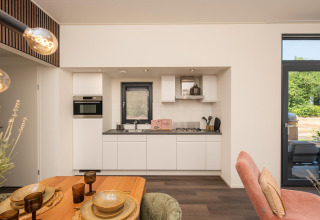 Moderne keuken en eethoek in de Cannenburch Deluxe-lodge bij de Bosgraaf, Nederland, licht en stijlvol ingericht.