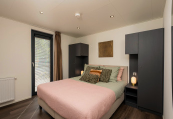 Moderne soveværelse på Cannenburch Deluxe-lodgen i de Bosgraaf, Holland, med dobbeltseng og stilfuldt interiør.