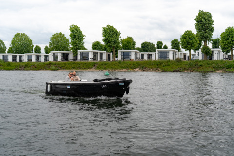 Ein Paar fährt in einem schwarzen Boot vor modernen Villen im MarinaPark Bad Nederrijn, Niederlande.