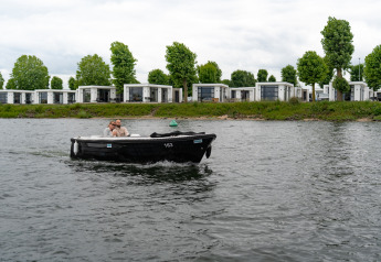 Een koppel vaart in een zwarte boot voor moderne huisjes bij MarinaPark Bad Nederrijn in Nederland.