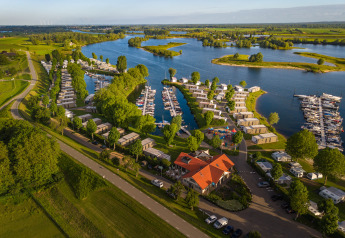 Luftaufnahme der Villa Maritiem Lodge an einem Fluss mit Hütten, Yachthafen und grüner Landschaft.