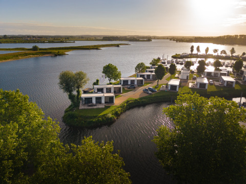 Tramonto presso il lodge Villa Maritiem con case moderne sul lago circondate da verde e acqua.