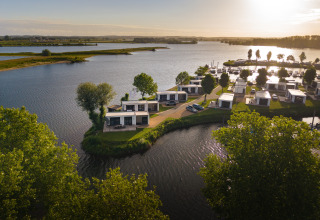 Tramonto presso il lodge Villa Maritiem con case moderne sul lago circondate da verde e acqua.