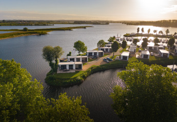 Sonnenuntergang über Villa Maritiem Lodge mit modernen Ferienhäusern am ruhigen See und viel Grün.