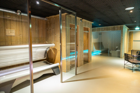 Photo of a relaxing wellness area with tanning beds and saunas at a glamping accommodation with wood walls.