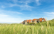 Casas de vacaciones en Breeduyn Village, Flandes Occidental, Bélgica, junto a dunas y cielo azul.