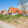 Modern holiday cottages with orange roofs and landscaped grounds at Breeduyn Village in Belgium.