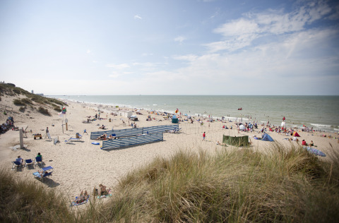 Strand met bezoekers aan Breeduyn Village vakantiepark in West-Vlaanderen, België, onder een zonnige hemel.