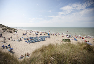 Strand mit Besuchern im Ferienpark Breeduyn Village in Westflandern, Belgien, unter sonnigem Himmel.