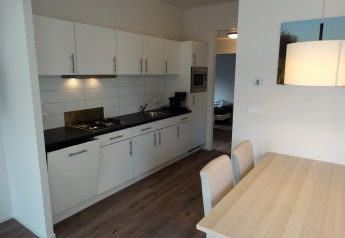 Moderne Küche mit Essbereich in Lodge 4 im Breeduyn Village, Belgien, weiße Schränke und Holzboden.