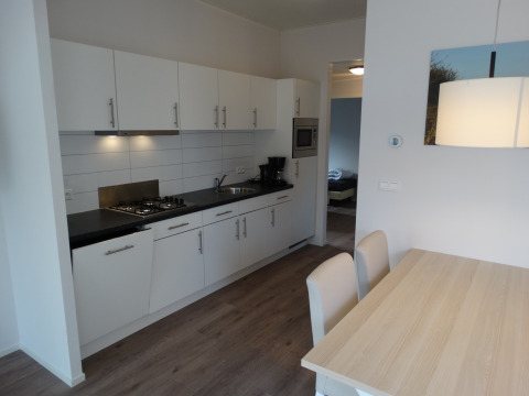 Moderne Küche mit Essbereich in Lodge 4 im Breeduyn Village, Belgien, weiße Schränke und Holzboden.