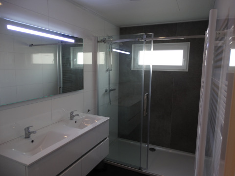 Modernes Badezimmer in Lodge 4 im Breeduyn Village, Belgien, mit Doppelwaschbecken und Duschkabine.