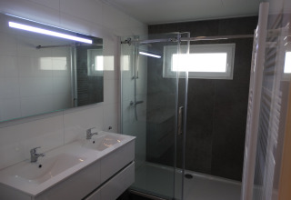 Modernes Badezimmer in Lodge 4 im Breeduyn Village, Belgien, mit Doppelwaschbecken und Duschkabine.