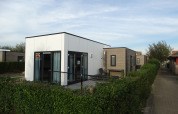 Lodge 4 moderne au Breeduyn Village en Belgique, entouré de haies et d’un chemin pavé sur le côté.
