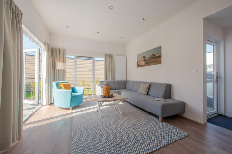 Helles, modernes Wohnzimmer in der Lodge 6 im Breeduyn Village, Belgien, mit großen Fenstern und stilvoller Einrichtung.