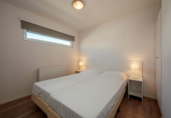 Slaapkamer in Lodge 6 in Breeduyn Village, België, met een dubbel bed, nachtkastjes en moderne sfeer.