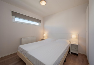 Camera da letto nella Lodge 6 al Breeduyn Village in Belgio con letto matrimoniale, comodini e arredamento moderno.