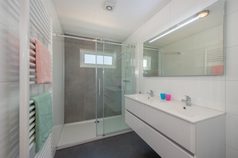 Modernes Badezimmer mit großer Dusche, Doppelwaschbecken und farbigen Handtüchern in Lodge 6, Breeduyn Village.