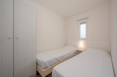 Schlichtes Schlafzimmer mit zwei Einzelbetten, Nachttisch und Kleiderschrank in Lodge 6, Breeduyn Village, Belgien.