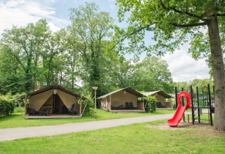 Familietenten en een rode glijbaan op Camping de Haer, vakantiedomein in Overijssel, Nederland.