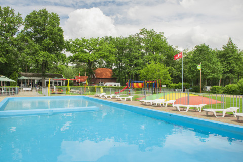Piscine extérieure et aire de jeux colorée au Camping de Haer, entourées d’arbres à Overijssel, Pays-Bas.