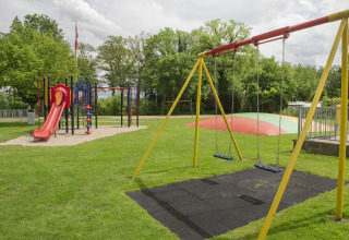 Speelplein bij Camping de Haer in Overijssel, Nederland, met schommels, glijbaan en springkussen.