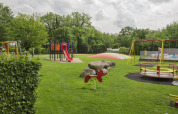 Parco giochi al Camping de Haer in Overijssel con scivolo rosso, altalene e tappeto elastico.