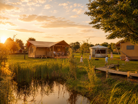 Tente glamping au Holiday park Eigen Wijze, aux Pays-Bas, au coucher du soleil, enfants jouant dehors.